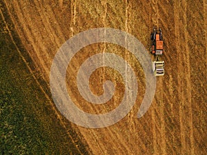 Aerial view of tractor making hay bale rolls in field