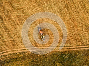 Aerial view of tractor making hay bale rolls in field