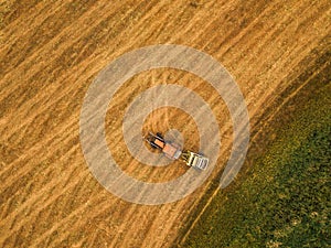 Aerial view of tractor making hay bale rolls in field