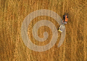 Aerial view of tractor making hay bale rolls in field