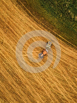 Aerial view of tractor making hay bale rolls in field