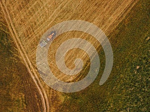 Aerial view of tractor making hay bale rolls in field