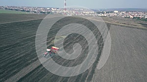 Aerial view of tractor with mounted seeder performing direct seeding of crops on plowed agricultural field.