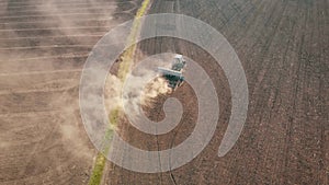 Aerial view of tractor with mounted seeder performing direct seeding of crops on plowed agricultural field. Technique