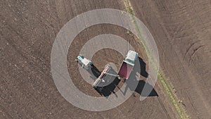 Aerial view of tractor with mounted seeder performing direct seeding of crops on plowed agricultural field. Technique