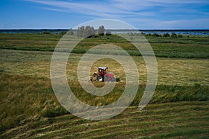 Aerial view of Tractor mowing green field in summer Finland