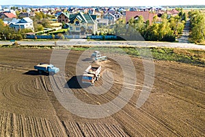 Aerial view of a tractor plowing black agriculture farm field after harvesting in autumn