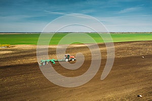 Aerial View. Tractor Plowing Field. Beginning Of Agricultural Spring Season. Cultivator Pulled By A Tractor In