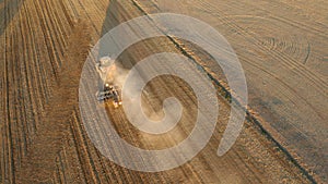 Aerial view of Tractor plowing field at sunrise. Shot on drone