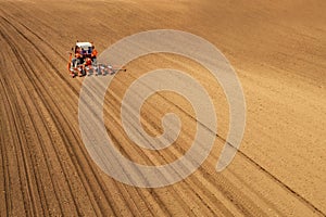 Aerial view of tractor sowing and planting corn in field