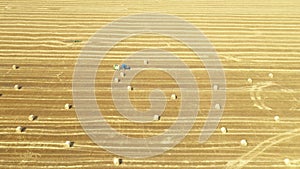 Aerial view of tractor tow trailed bale machine to collect straw from harvested field