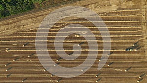 Aerial view of tractor tow trailed bale machine to collect straw from harvested field