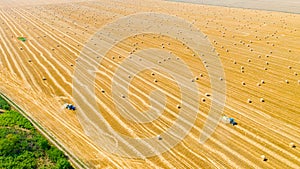 Aerial view of tractor tow trailed bale machine to collect straw from harvested field