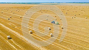 Aerial view of tractor tow trailed bale machine to collect straw from harvested field