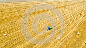 Aerial view of tractor tow trailed bale machine to collect straw from harvested field