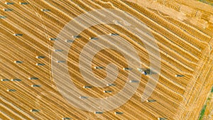 Aerial view of tractor tow trailed bale machine to collect straw from harvested field