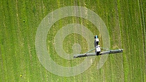 Aerial view tractor trailed sprayer drives on field