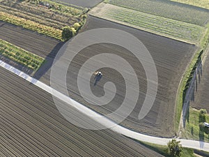 Aerial view of a tractor working in an agricultural field at sunset near Aquileia, Udine, Friuli Venezia Giulia, Italy