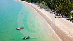 Aerial view of traditional Thai longtail fishin boats moored off a small, palm tree lined tropical beach (Khao Lak, Thailand