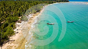 Aerial view of traditional Thai longtail fishin boats moored off a small, palm tree lined tropical beach (Khao Lak, Thailand