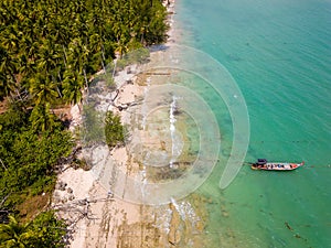 Aerial view of traditional Thai longtail fishin boats moored off a small, palm tree lined tropical beach (Khao Lak, Thailand