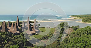 Aerial view of traditional village with ornately houses roof on sand beach sea shore, tropic forest