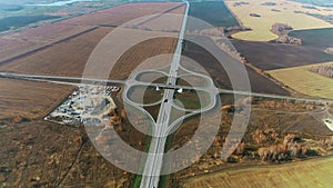 Aerial view of a traffic intersection. Trucks and cars drive along the highway. Top view on the highway on a sunny day