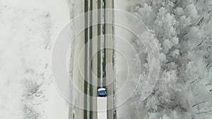 Aerial view of traffic on the road passing through the winter forest in severe weather. Scene. Top view of a cargo truck