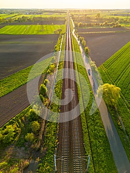Aerial view of train tracks in a green field on a sunny day