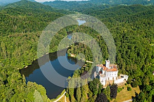 Aerial view of Trakoscan castle surrounded by the lake and forested hills