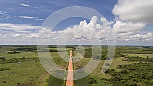 Aerial view of Transpantaneira dirt road crossing straight the North Pantanal Wetlands, blue horizon with white clouds, Mato