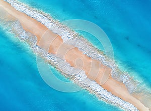 Aerial view of blue sea with waves on the both sides at sunset