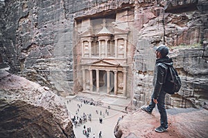 Aerial view of Treasury with a hiker, solo traveler, young man tourist on a cliff after reaching the top, Al Khazneh in the