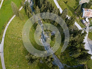 Aerial view on trees, paths, a creek and a hut used by people for refreshment in the skiing region of Hinterglemm in the