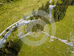 Aerial view on trees, paths and a creek used by people for refreshment in the skiing region of Hinterglemm in the Alps