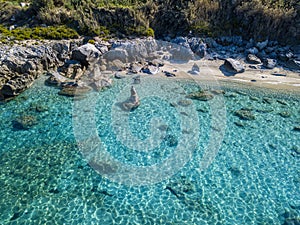 Aerial view of Tropea beach, crystal clear water and rocks that appear on the beach. Calabria, Italy. Swimmers, bathers floating