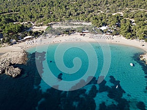 Aerial view of a tropical beach with crystal clear blue water alongside lush green forest