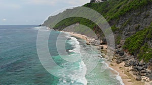 Aerial view of tropical beach with rocks and ocean.