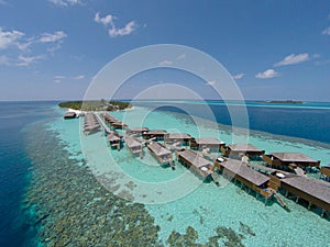 Aerial view of a tropical island in turquoise water. Luxurious over-water villas on tropical island resort maldives.