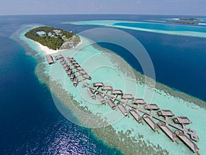 Aerial view of a tropical island in turquoise water. Luxurious over-water villas on tropical island resort maldives for holiday.