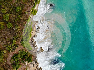 Aerial view of tropical sand beach with rocks and green cliff