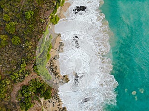 Aerial view of tropical sand beach with rocks and green cliff