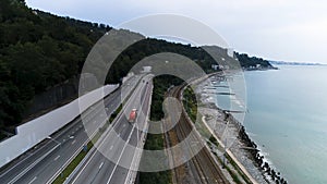 Aerial view of a truck driving on the road along the sea coast and rails, transportation concept. Scene. Cars moving on