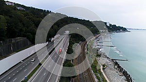 Aerial view of a truck driving on the road along the sea coast and rails, transportation concept. Scene. Cars moving on