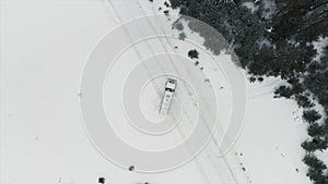 Aerial view of a truck parked across the road surrounded by winter forest. Clip. Cargo truck stopped on a snow covered