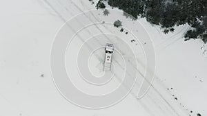 Aerial view of a truck parked across the road surrounded by winter forest. Clip. Cargo truck stopped on a snow covered