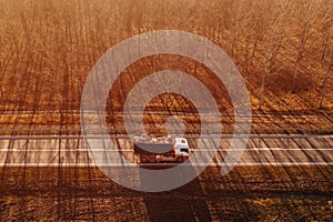 Aerial view of truck with waste paper loaded in wagon driving through wooded autumn scenery