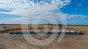 Aerial view of trucks prepared to load corn grains after harvest in the field.