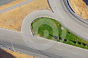 Aerial view of the turning of asphalt roads with white markings, metal fences and signs