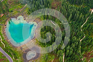 Aerial view of turquoise blue water of lake Carezza in Alps Dolomites. Lago di Karersee near fir tree forest photo